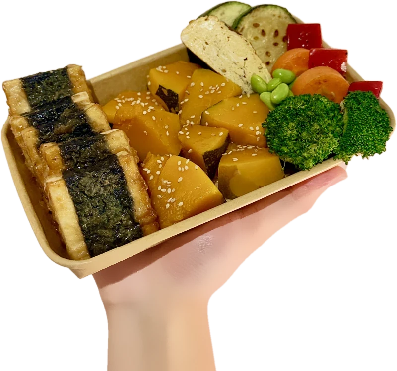 Hand holding a Power Bento with nori-wrapped teriyaki tofu, pumpkin, tamagoyaki and vegetables
